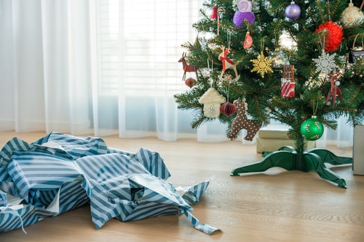 Torn Christmas wrapping paper mess near tree symbolizing holiday excess, paper overuse, copy space photo