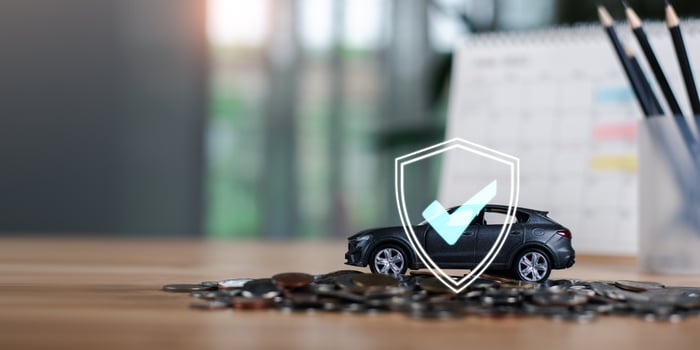 Car insurance and financial risk protection concept. A toy car on coins with a digital shield icon symbolizes security, accident coverage, and vehicle investment protection. photo