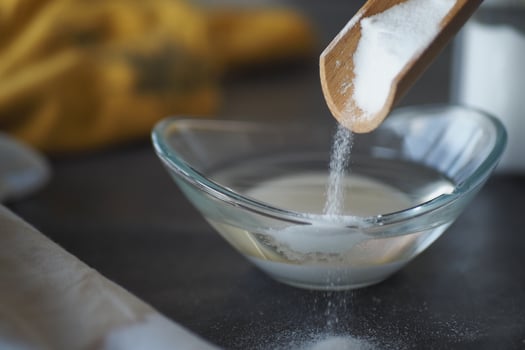 Pouring baking soda powder into a clear bowl photo