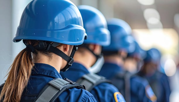 Disciplined group of persons uniform stand line, wearing blue helmets. Their collective presence conveys sense of protection and readiness for security, showing determined team committed to duty photo