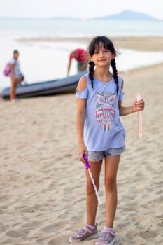 Young Girl with Bubble Wand on Serene Beach at Dusk photo