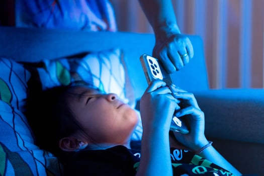 Parent taking smartphone from child at night in bed, concept of screen time limits, digital detox, and bedtime struggle photo