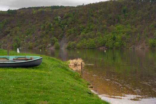 Rowboat on grassy riverbank with forest view at Nova Zivohost photo