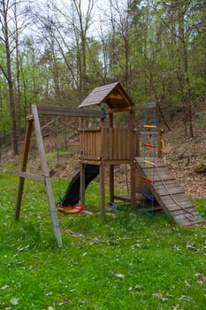 Wooden playground set with swing, slide, and climbing rope in forest park setting during spring photo