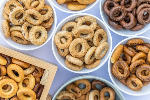 Freshly baked mini bagels on a dark background. Top view. Pretzels in the form of a ring close-up. Small bread circle biscuit. Bowls with different types of bagels. photo