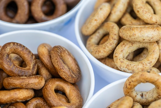 Bowls with different types of bagels on a blue background photo