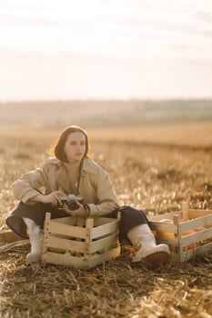 Portrait of stylish woman in a coat takes photographs on an autumn field. Autumn harvest. photo