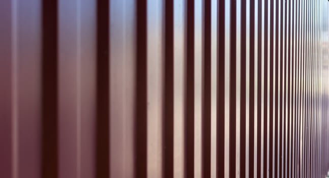 A modern corrugated metal panel fence with a vertical, repetitive pattern. photo