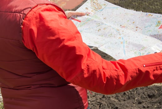 Woman in a red jacket holding cards while traveling, trip photo