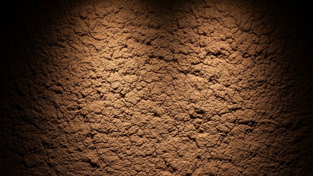 A dark brown wall with dirt and light photo