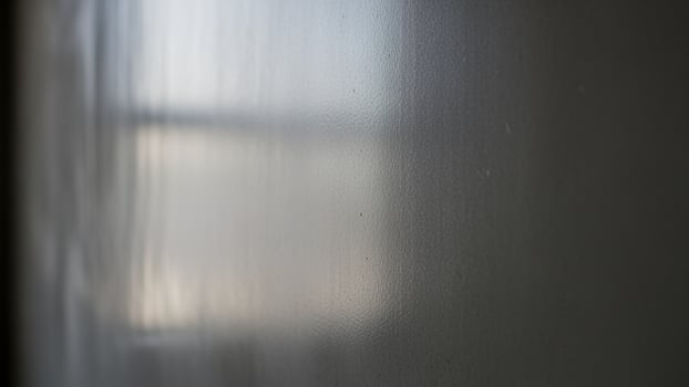 A blurry photo of a window with a white curtain