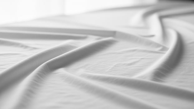 A white sheet is folded over a bed photo