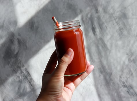 Red tomato juice glass in woman hand. Healthy antioxidants drinking. photo