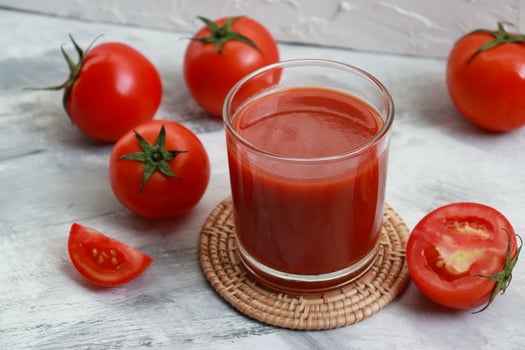 Red tomato juice glass with fresh ripe tomato on table. photo