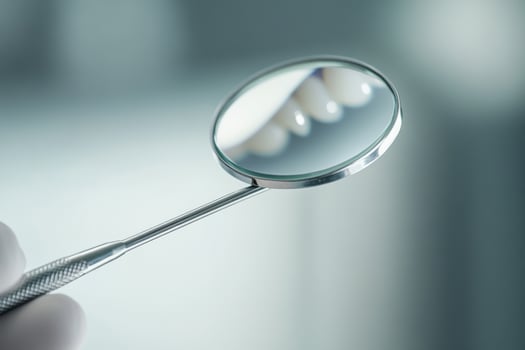 A person holding a magnifying glass over a tooth photo