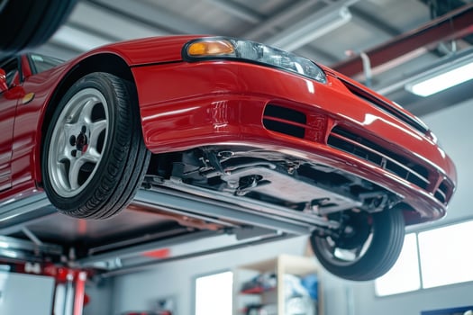 A red car is being lifted up on a lift photo