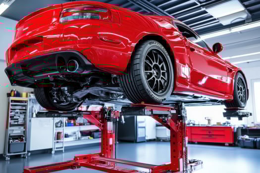 A red car is being lifted on a lift in a garage photo