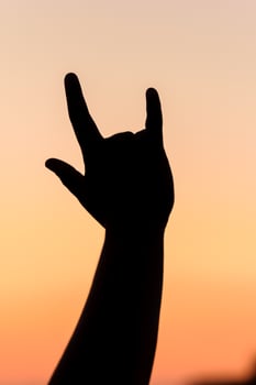 Silhouette of a hand making a rock-on sign, summer concert feeling. Celebrating life and music at sunset, freedom and joy. photo