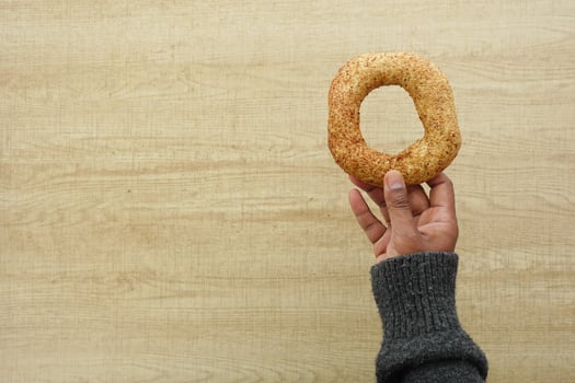 Hand holding a freshly baked bagel on a wooden table photo
