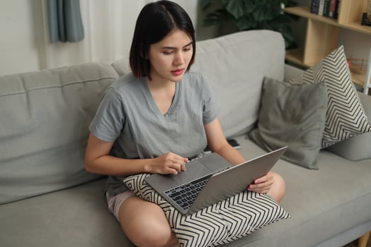 Top view, Asian woman in casual clothes using laptop while sitting on sofa in cozy living room. Work from home, Remote working. photo