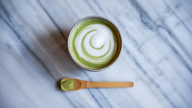 Creamy matcha latte with swirls and wooden spoon photo