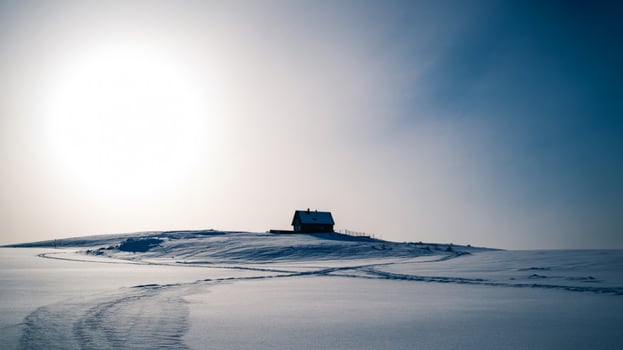 Solitary cabin on a snow covered hill under a bright sky photo