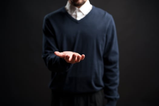 Man in sweater holds out hand in studio setting conveying invitation or request during a storytelling moment photo