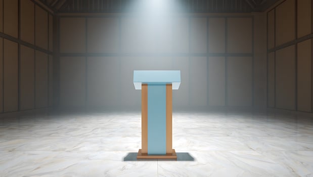 Empty podium bathed in dramatic spotlight in a dim hall photo