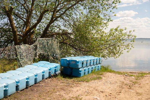 Blue plastic container stack by lake shoreline with greenery photo