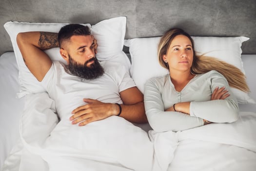 A young couple lies on the bed during a serious argument, both looking frustrated and distant. The atmosphere is tense, reflecting real life relationship struggles and emotional conflict. photo