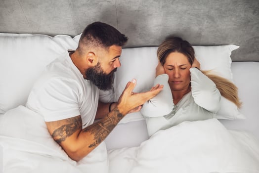 A young couple engaged in a heated argument while lying on the bed, showing frustration and tension in their relationship. photo