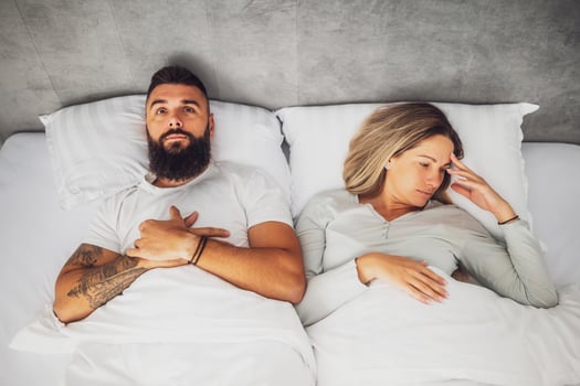 A heterosexual couple lies on a couch, avoiding eye contact, expressing displeasure and unresolved conflict in their relationship. photo