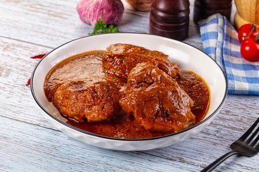 A bowl of meat and sauce on a table photo