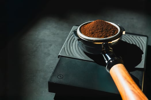 Coffee grounds in basket of portafilter on a weighing scale in dark background. photo