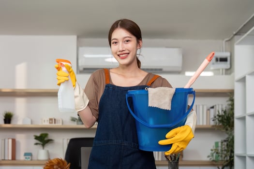 Home Cleaning. Young woman holding cleaning supplies and smiling. photo