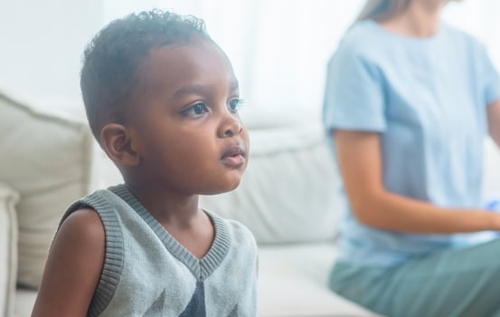 young boy is sitting on couch with his eyes closed photo