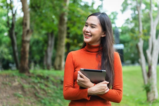 woman in orange sweater is holding tablet in her hand photo