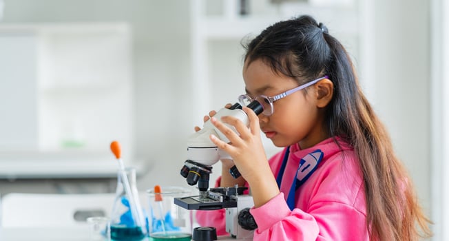 girl is looking through microscope photo