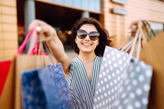 Young woman with shopping bags walking in front of a city building photo