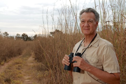 Field Biologist doing Research monitoring the environment in a Tall Grassy area using Binoculars in the Savannas of Brazil photo