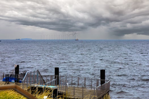 Sea view in cloudy weather with grey clouds and windmills in the distance photo