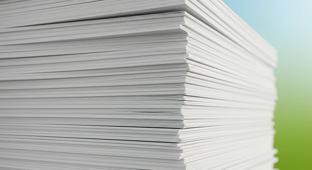 Detailed corner view of a towering stack of white paper against a soft blue-green gradient. photo