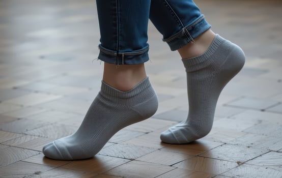 A woman's legs in grey socks standing on a wooden floor photo