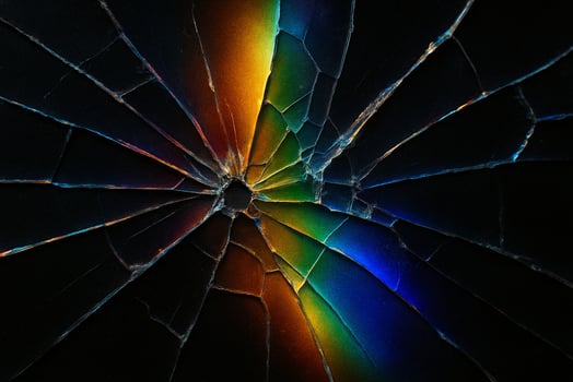 Macro photo of shattered glass reflecting vivid rainbow light. Abstract composition with colorful prism refraction and sharp angular cracks on a black background.