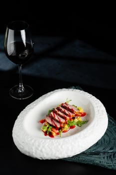 Sliced Duck Breast with Fruit Salsa and Red Wine on Dark Background photo