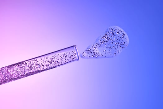 The texture of cosmetic serum in a test tube on a blue-purple background. photo