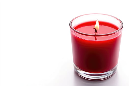 A lit red candle in a glass jar, isolated on white background photo