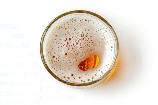 Top view of a glass of beer with foam and a slice of orange, isolated on white background photo