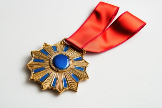 Ornate gold medal with blue accents and red ribbon isolated on white background photo