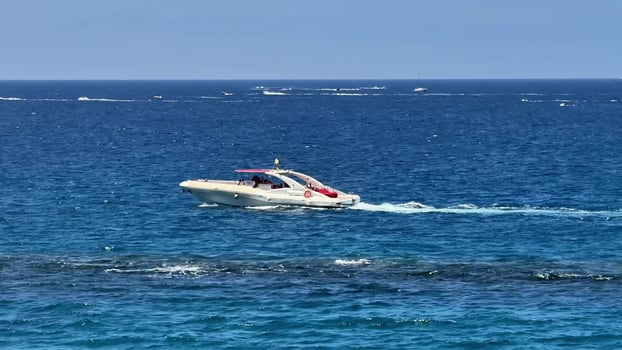 A sleek and fast boat is gracefully gliding over the shimmering and sparkling ocean waters on a bright sunny photo